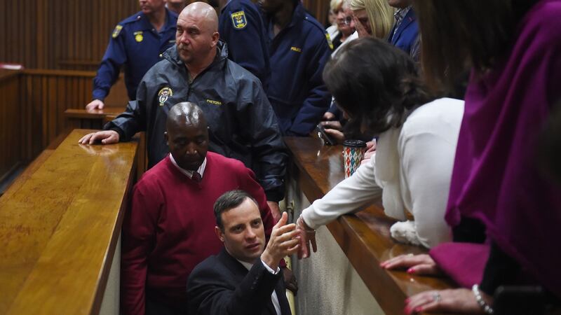 Oscar Pistorius reaches out to touch the hand of a family member as he makes his way to the holding cells after he was sentenced to six years imprisonment for killing his girlfriend Reeva Steenkamp. Photograph: AFP/Getty Images