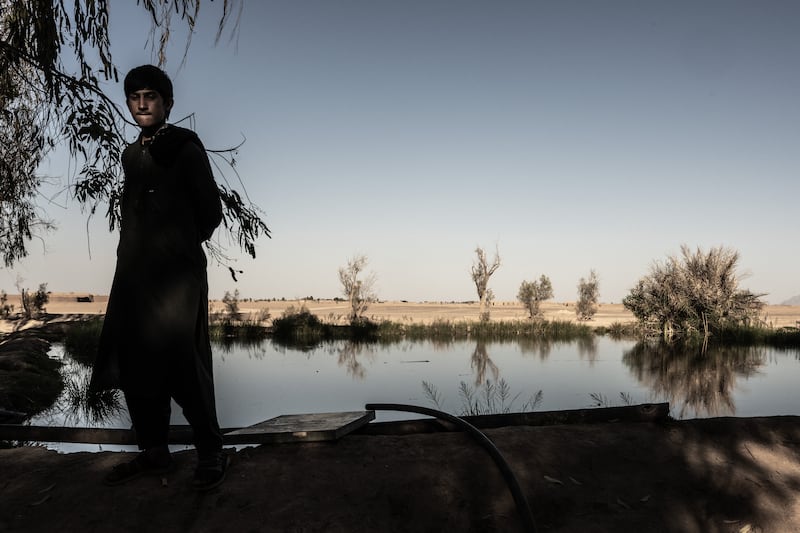 A young man standing near a private reservoir, fed by water pumped by solar power, with dry fields surrounding it, in southwest Afghanistan’s arid Bakwa district on April 22nd, 2023. Photograph: Bryan Denton/The New York Times
                      