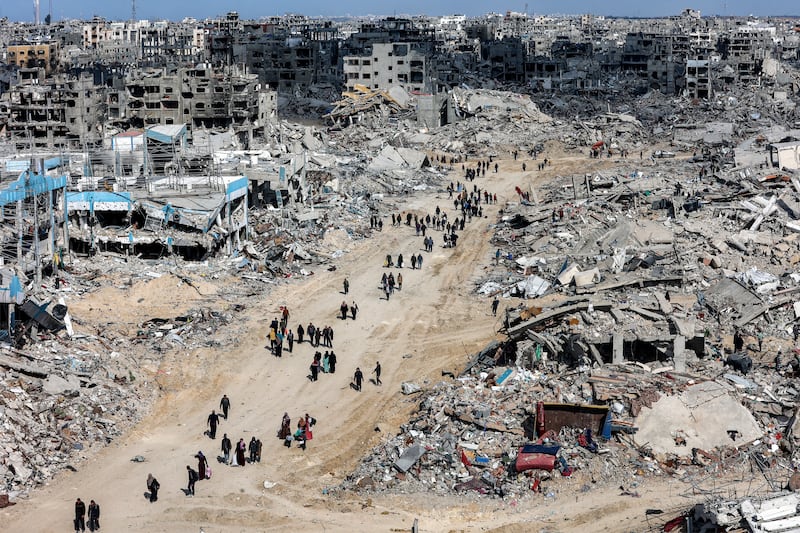 People walk past rubble of collapsed buildings near a destroyed clinic of the United Nations Relief and Works Agency for Palestine Refugees (UNRWA) at the Jabalia camp for Palestinian refugees in the northern Gaza Strip on Sunday after a ceasefire deal in the war between Israel and Hamas was implemented. Photograph: Omar Al-Qattaa/AFP/Getty