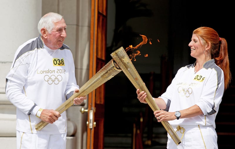 Olympic Gold medal winner Ronnie Delany passes the Olympic flame to Katie Taylor's mother Bridget at Goverment Buildings in 2012. Photograph: Cathal Noonan/Inpho