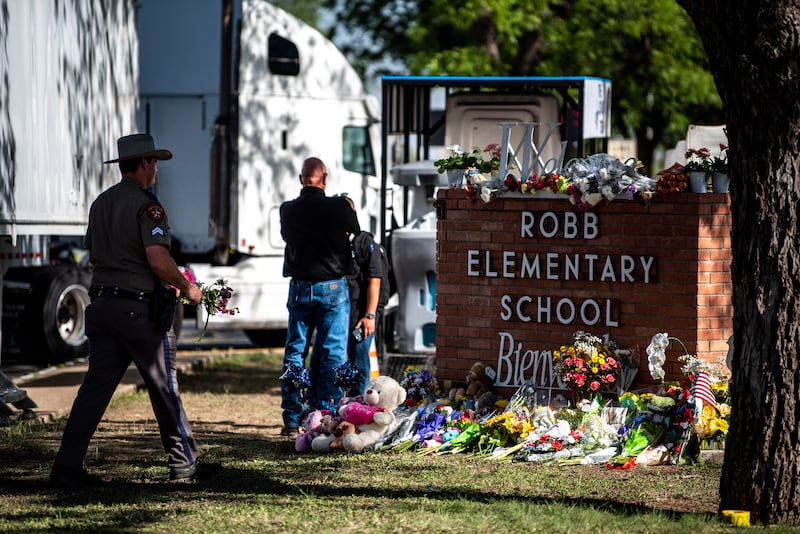 A state trooper with the Texas High Patrol carries a bouquet of flowers to a makeshift memorial outside Robb Elementary School in Uvalde on Wednesday. Photograph: Meridith Kohut/The New York Times