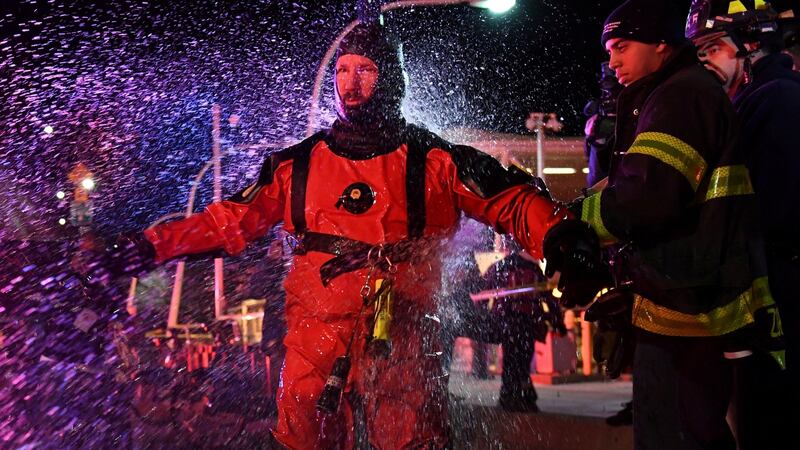 A New York Fire Department rescue diver is hosed off with fresh water after pulling victims from a submerged helicopter after it crashed into the East River in New York. Photograph: Reuters