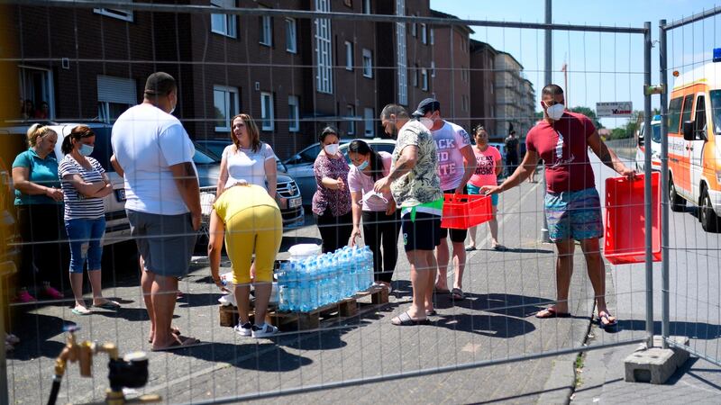 People, under quarantine after a coronavirus outbreak at a slaughterhouse of the Tönnies company, receive goods. Photograph:  Ina Fassbender/AFP via Getty Images