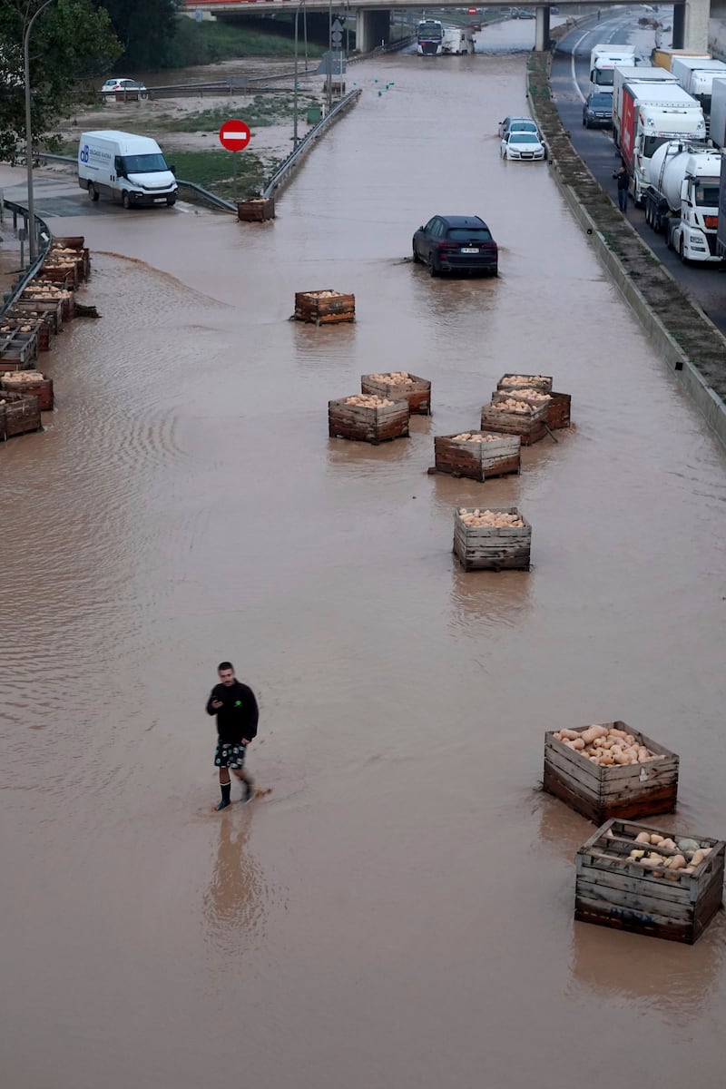 A man walks on a flooded motorway in Valencia. Photograph: Alberto Saiz/AP