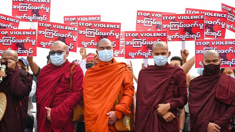 Buddhist monks stand in front of protesters holding signs during a demonstration against the military coup in Yangon’s Hlaing Tharyar township on March 14th. Photograph:  STR/AFP via Getty Images