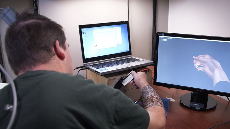 Ian Burkhart (24) – who has regained functional use of his hand through the use of neural bypass technology – swiping a credit card. Photograph: Ohio State University/Batelle