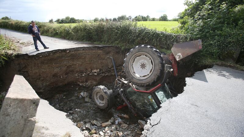 A man looks at a tractor which has fallen into a river after a road collapsed in Iskaheen, Co Donegal after heavy rain left a trail of destruction. Photograph: Niall Carson/PA Wire