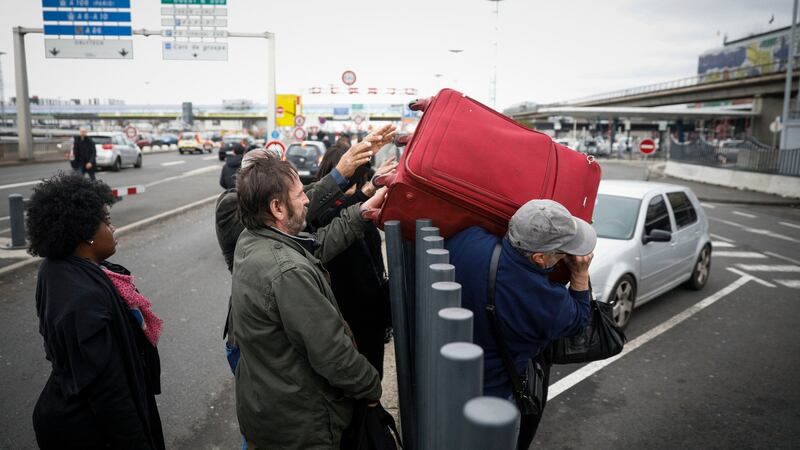 Travellers hand their luggage to friends  over a fence as they walk back into Orly airport, south of Paris, when flights began to resume on Saturday. Photograph: Kamil Zihnioglu/AP