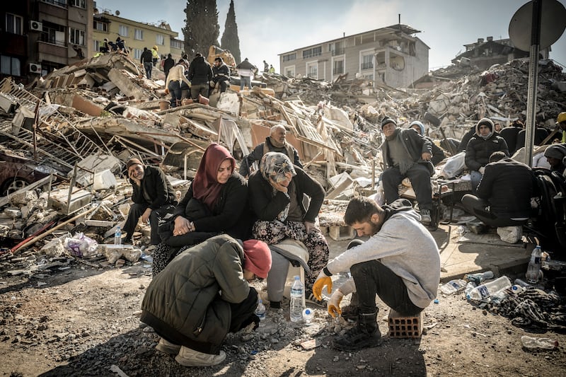 Displaced residents sit near their collapsed home as rescue operations continue in Antakya, Turkey. Photograph: Sergey Ponomarev/The New York Times