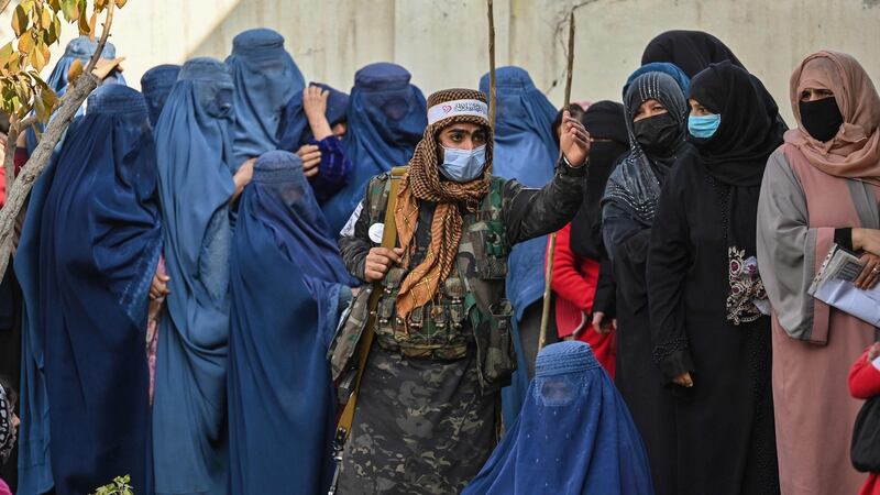 A Taliban fighter on guard as women wait in a queue during a World Food Programme cash distribution in Kabul in November. Photograph: Hector Retamal