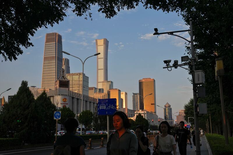 People walk near the Central Business District during the rush hour in Beijing (Andy Wong/AP)