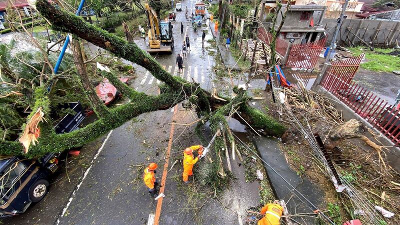 Emergency workers clear a toppled tree in the  town of Tigaon, Camarines Sur, in the  Philippines. Photograph: EPA