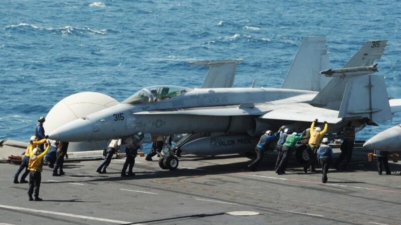 Sailors guiding an F/A-18C Hornet assigned to the Valions of Strike Fighter Squadron (VFA) 15 on the flight deck of the US aircraft carrier USS George H.W. Bush (CVN 77), in the Arabian Gulf today. Photograph: Lorelei Vander Griend/US Navy/EPA