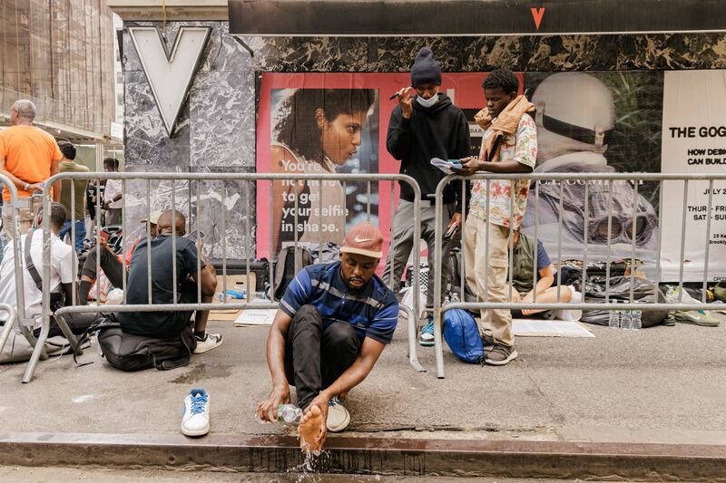 A migrant washes his feet outside the Roosevelt Hotel. Photograph: Jeenah Moon/The New York Times                      