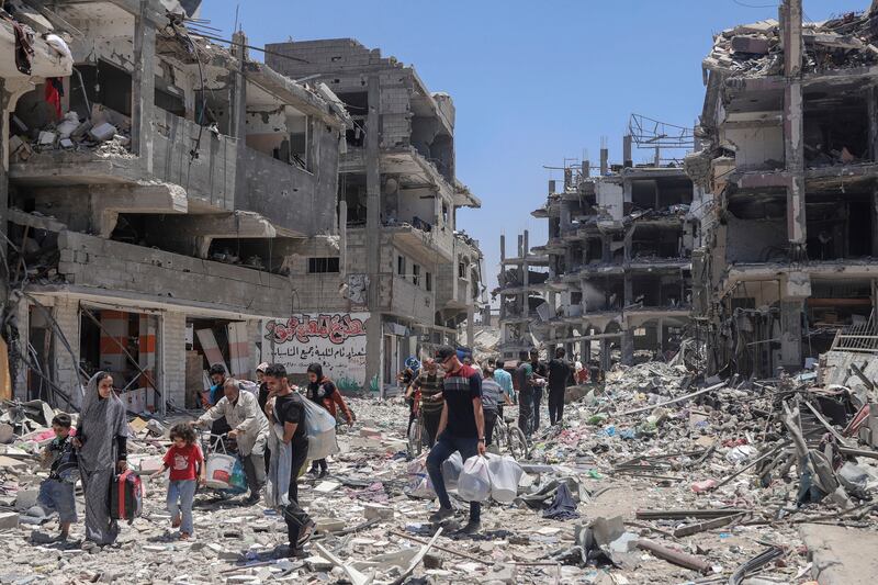 Palestinians walk through the destruction in the wake of an Israeli air and ground offensive in Jibalia in Gaza in May. Photograph: Enas Rami/AP