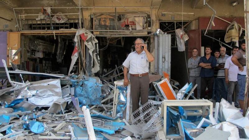 Residents stand among debris at one of the scenes of car bomb attacks that struck Baghdad today. Photograph: Ahmed Malik/Reuters.