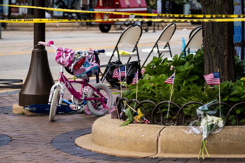 Flowers on a kerb near a child’s bicycle as members of the FBI’s Evidence Response Team Unit investigate the scene. Photograph: Ashlee Rezin/Chicago Sun-Times/AP