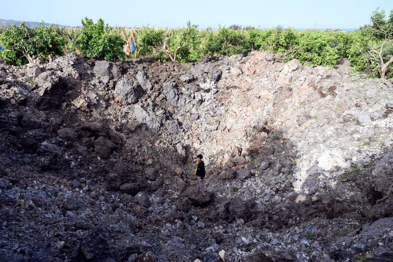 A Lebanese child stands in a deep crater after an Israeli airstrike in Alqulaylah village, southern Lebanon. Photograph: Wael Hamzeh/EPA