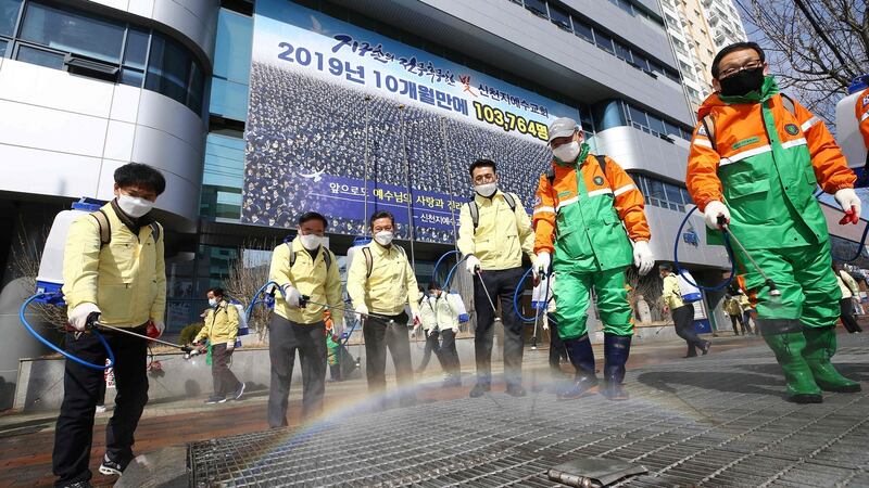 South Korean government officials spray disinfectant in front of the Daegu branch of the Shincheonji Church of Jesus Photograph: YONHAP/AFP via Getty Images